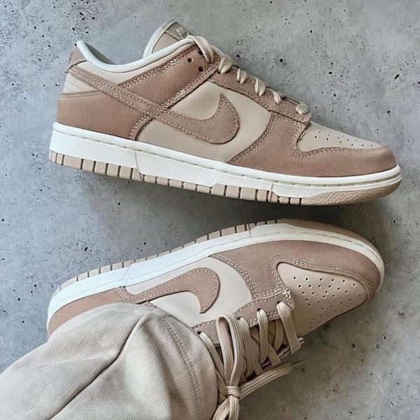 Beige Nike sneakers on a gray concrete floor, shown from the side and a close-up of the toe box, laces tied loosely.