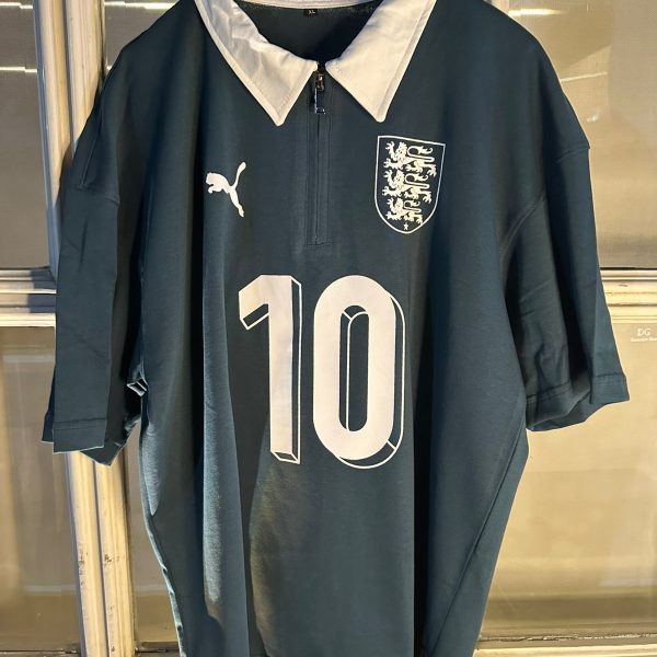 Dark teal England football jersey on a hanger with a white collar, featuring a left chest crest and large number 10 on the front.