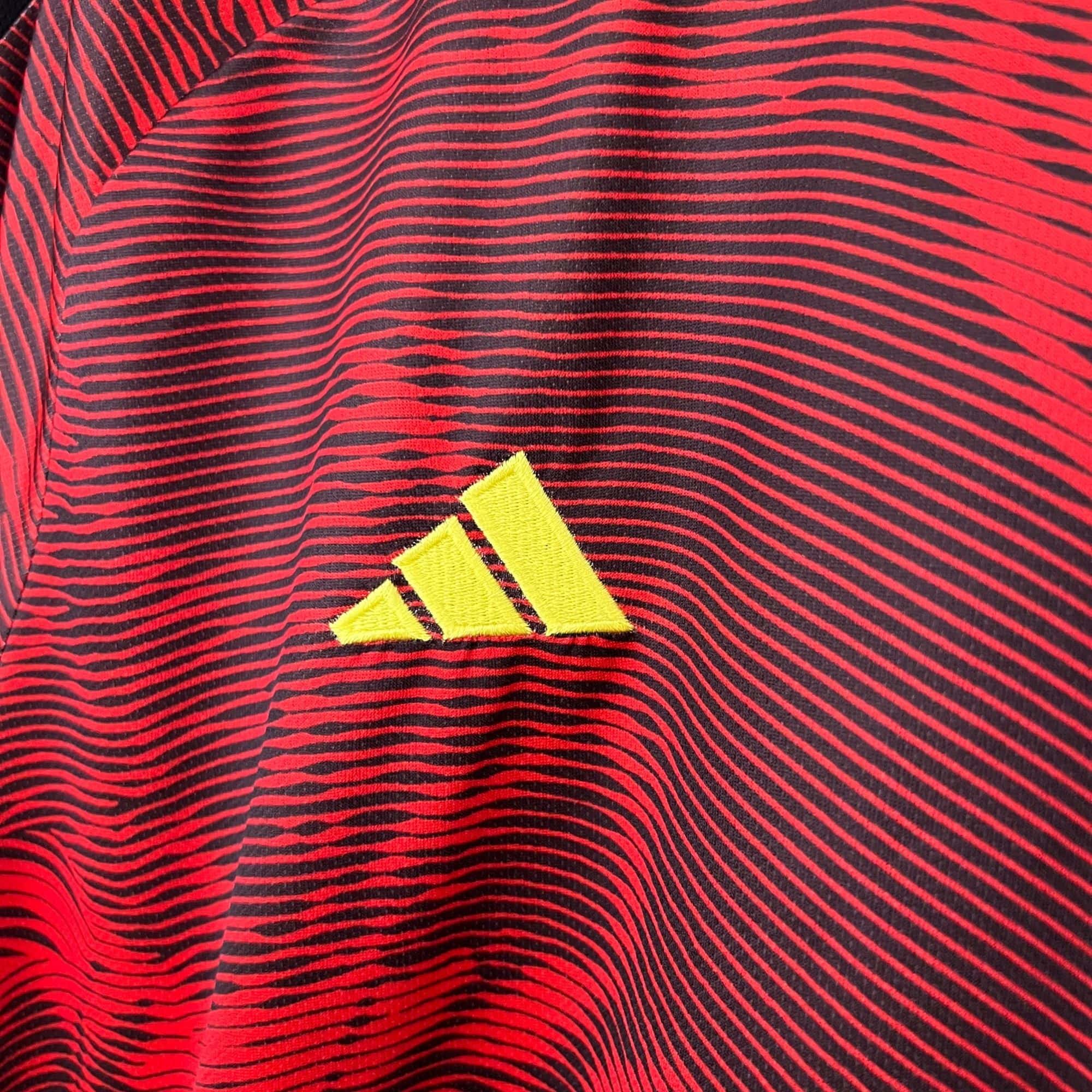 f1b055a5_64f6a4de-13e1-4806-8e80-0cfef6d85075 | UAE SPORT STORE Close-up of red and black horizontal stripes on fabric with a yellow triangular patch at the bottom.