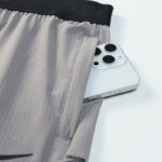 Light gray athletic shorts with a smartphone partially tucked into the side pocket.