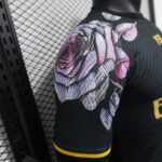 Close-up of black athletic fabric with a purple-pink floral pattern and yellow trim on the sleeve, with a mesh grid background behind it.