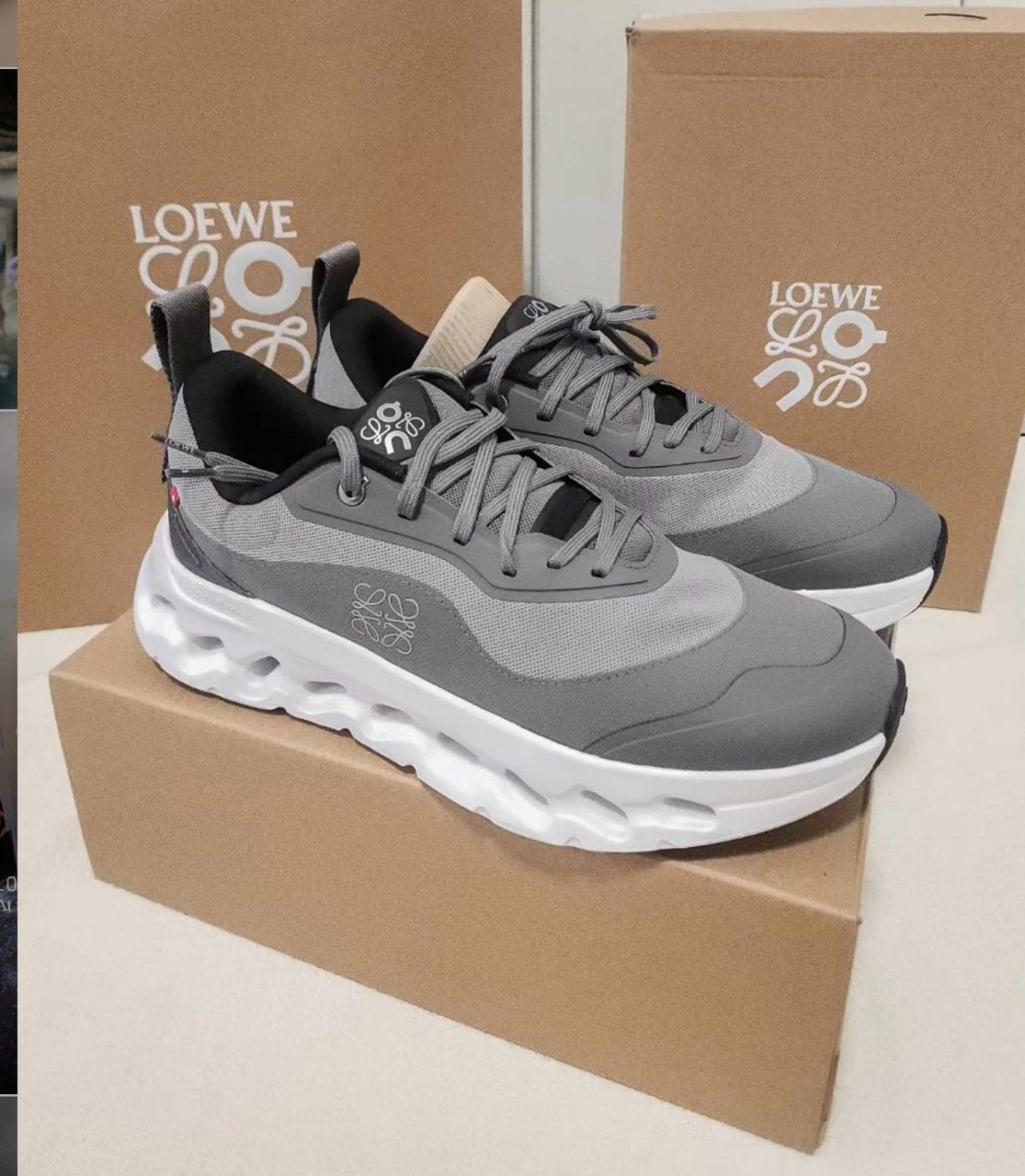 Gray Loewe sneakers with a thick white sole displayed on a brown shoebox; logo visible on the side and tongue.