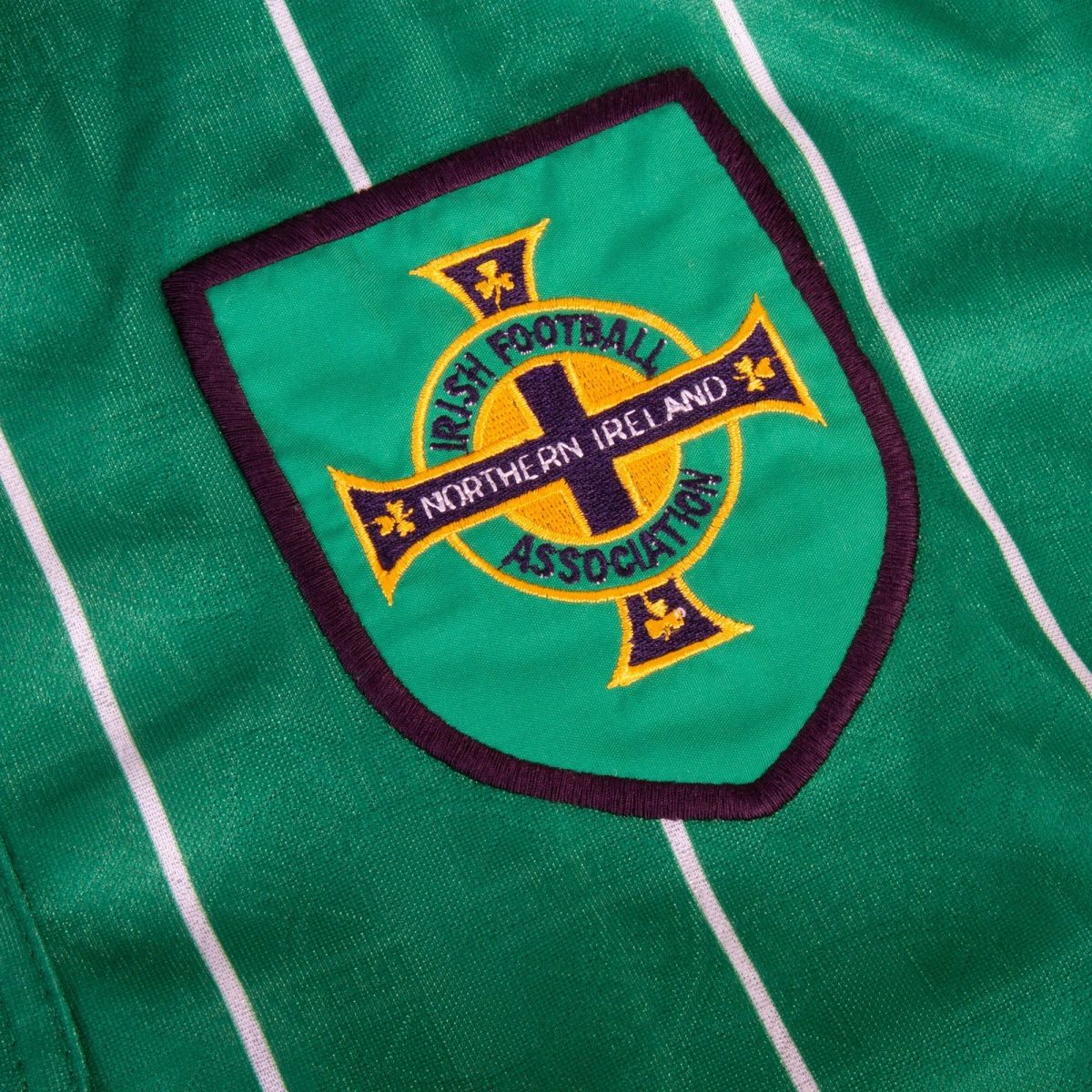 Close-up of a green embroidered badge on fabric featuring a circular emblem that reads Northern Ireland Football Association.