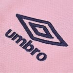 Close-up of pink fabric with a navy embroidered diamond logo and the word 'unhomo' beneath it.