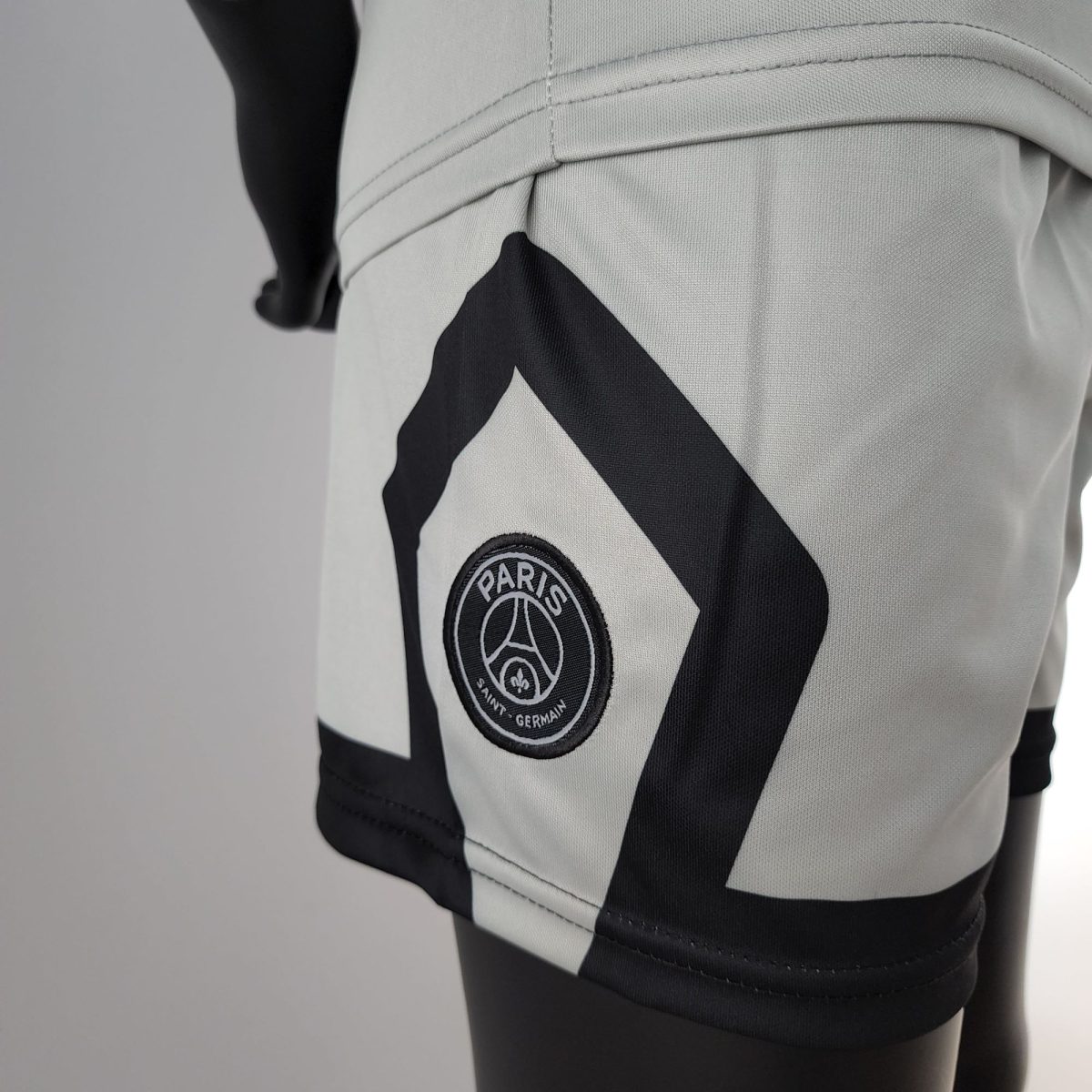 Close-up of a white Paris Saint-Germain jersey with a large black diagonal stripe and the club crest visible on the fabric edge.