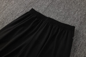 Black athletic shorts with an elastic waistband on a gray carpet surface, photographed from above.