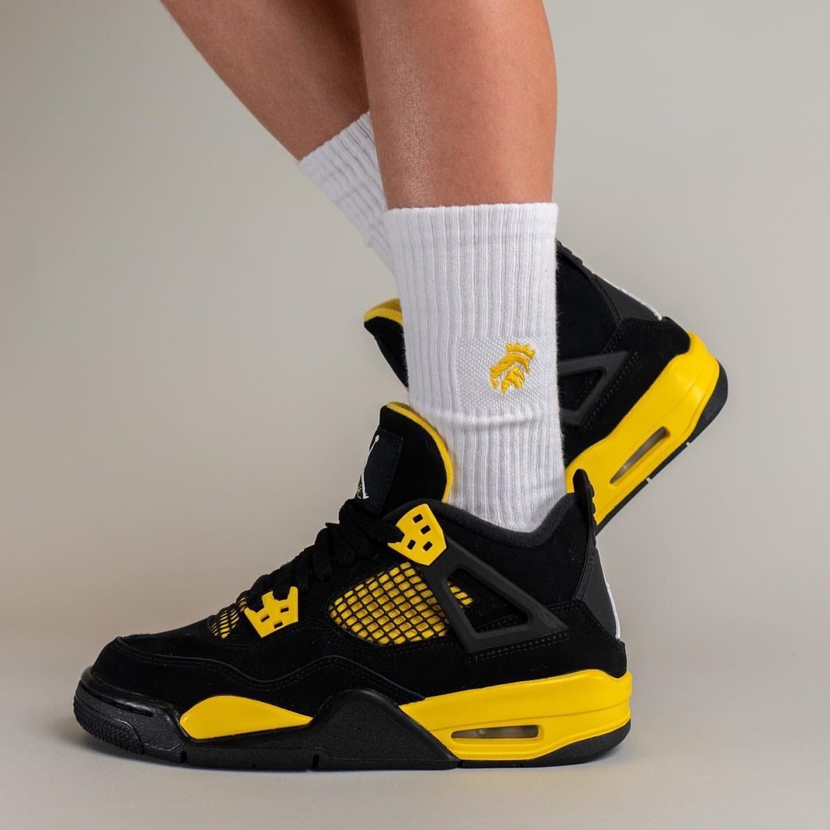 Close-up of a person wearing white socks and black-and-yellow sneakers, focusing on the feet and lower legs.