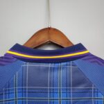 Blue plaid shirt on a wooden hanger, close-up of the collar against a light wall.