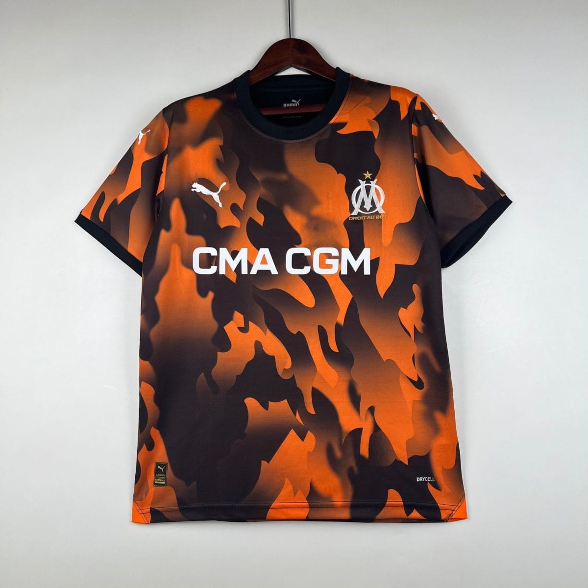 Orange and black camouflage football jersey on a hanger, displaying the OM crest and CMA CGM text across the front.