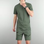 f572574b | UAE SPORT STORE Partial body of a man in olive-green athletic wear against a gray backdrop, with visible Nike swoosh on shorts and 'JUST DO IT' text on the leg.