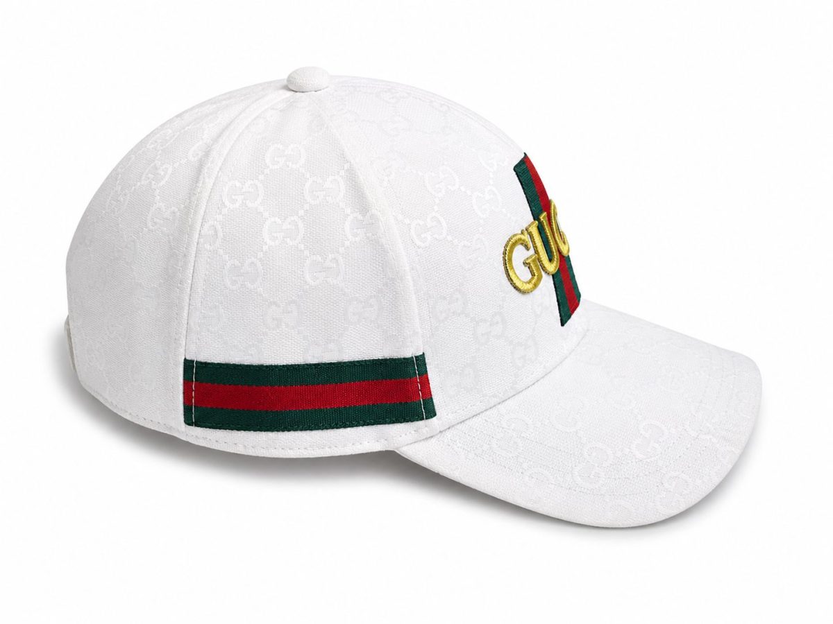 White Gucci baseball cap with an embossed GG pattern, green-red stripe on the back, and gold Gucci lettering on the front.