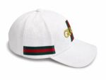 White Gucci baseball cap with embossed GG monogram, red-green stripe, and gold Gucci lettering on the front panel