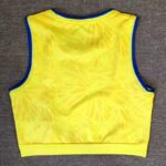 Back view of a bright yellow sleeveless athletic crop top with blue trim along the armholes and neckline. The shirt has a subtle abstract pattern.