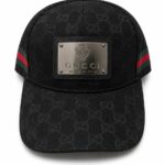 Black Gucci cap with all-over GG pattern and a metal plaque reading 'GUCCI made in Italy' on the front.