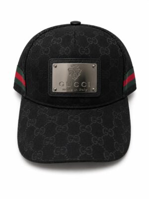 Black Gucci cap with all-over GG pattern and a metal plaque reading 'GUCCI made in Italy' on the front.
