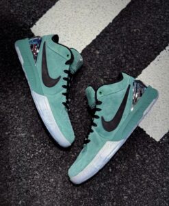 Mint green Nike high-top sneakers with a black swoosh, placed on dark asphalt next to a white painted line, showing a metallic heel detail on the right shoe.