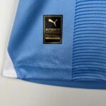 Close-up of blue sports jersey fabric with a black and gold patch showing the Puma logo and text 'AUTHENTIC LICENSED FOOTBALL'