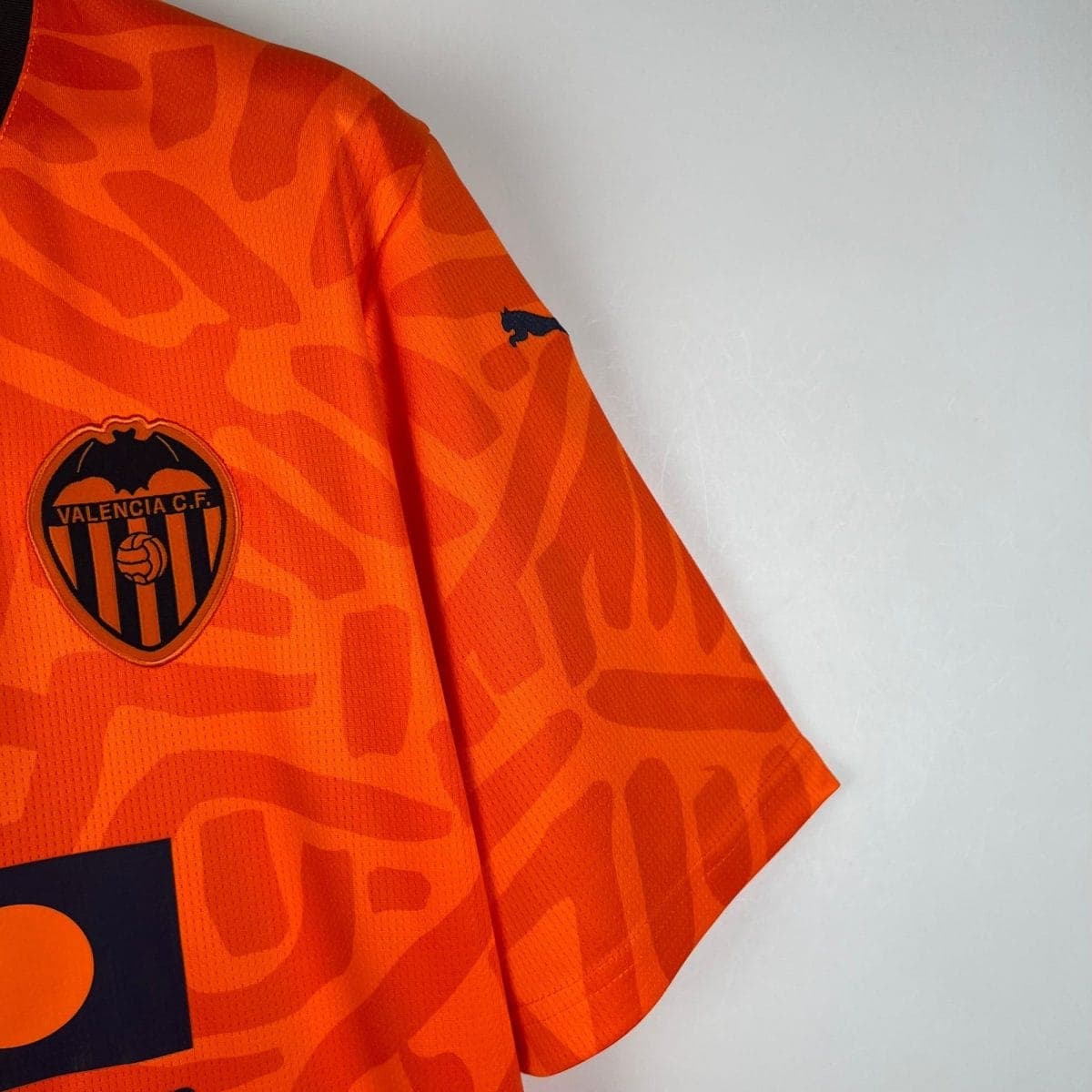Close-up of an orange Valencia CF football jersey, showing the club crest on the chest.