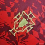 Mint-green embroidered geometric hexagon logo on red-purple camouflage fabric.