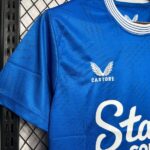 Blue Castore sports jersey on a rack, showing the white Castore logo with wings and partial white script text.