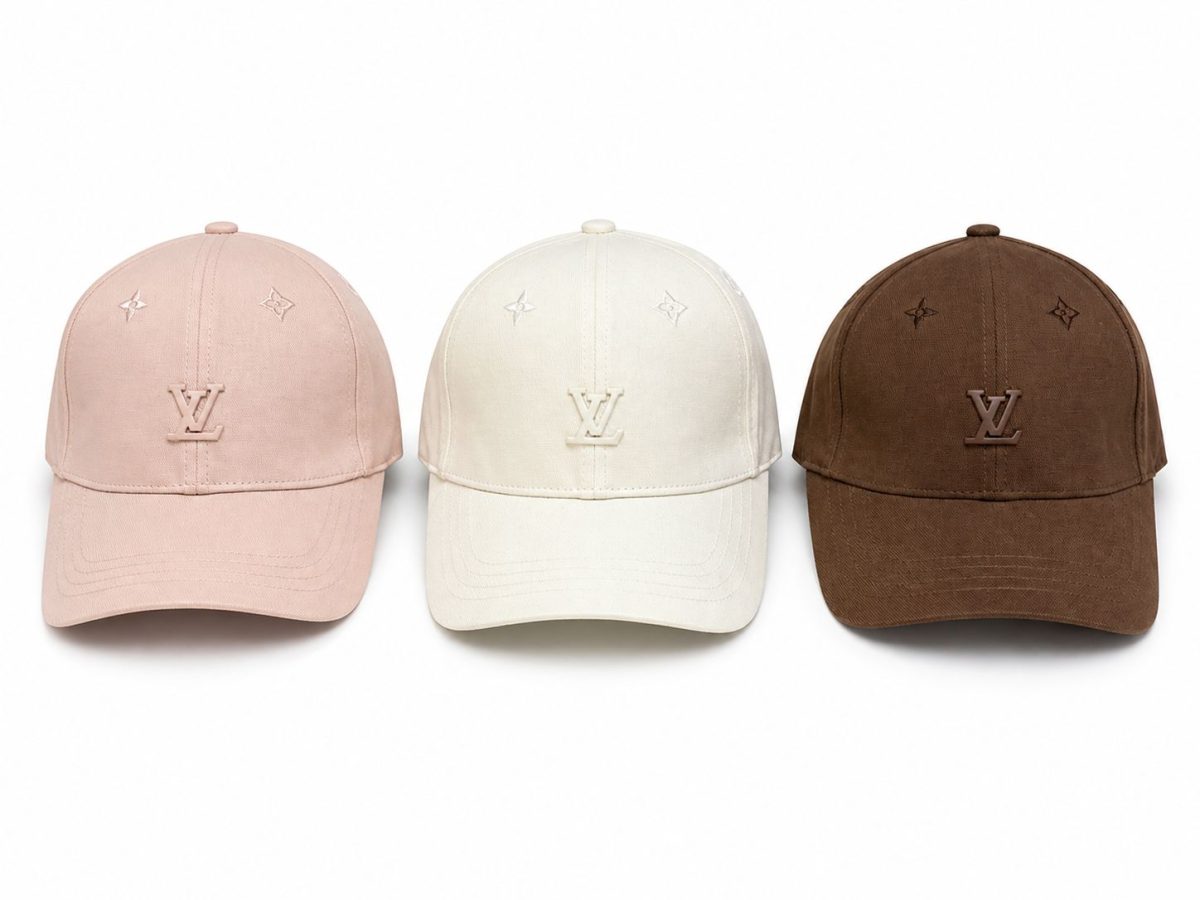 Three Louis Vuitton baseball caps in pink, white, and brown with the LV logo on the front panels.