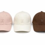 Three Louis Vuitton baseball caps in pink, white, and brown with the LV logo on the front panels.