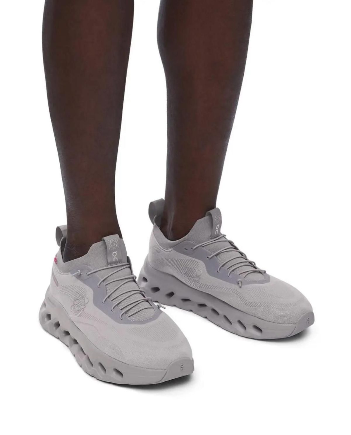 Dark-skinned legs wearing light gray athletic sneakers with thick, rounded soles.