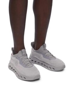 Dark-skinned legs wearing light gray athletic sneakers with thick, rounded soles.