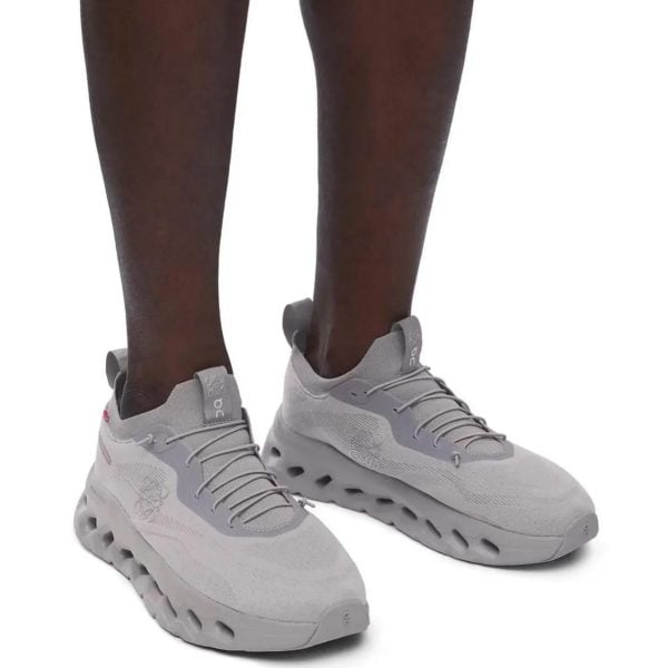 Dark-skinned legs wearing light gray athletic sneakers with thick, rounded soles.