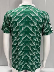 Back view of a green short-sleeve athletic jersey with a white speckled chevron/zigzag pattern across the entire back.