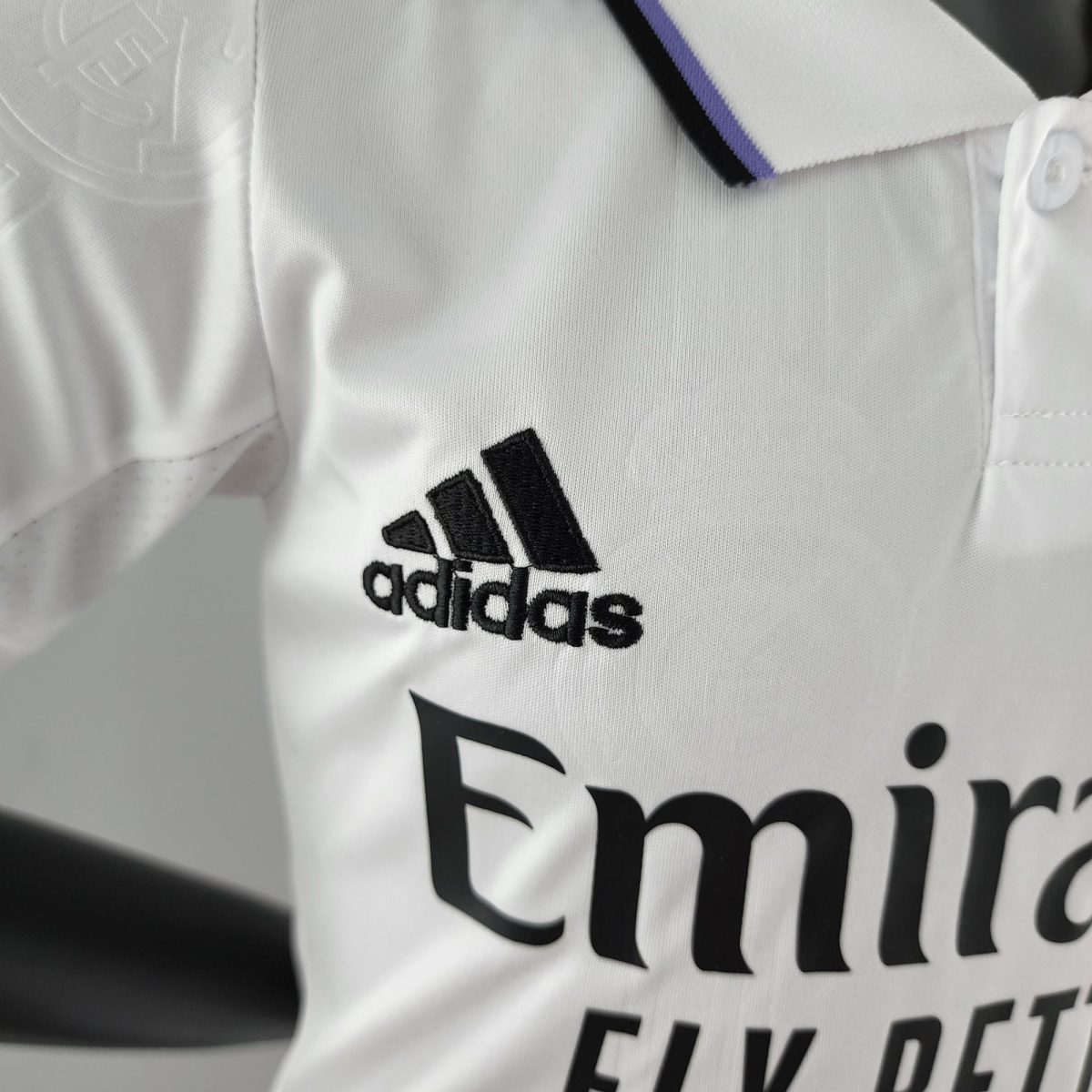 Close-up of white fabric with the black Adidas logo and wordmark printed on it.