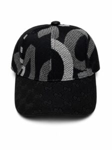 Black baseball cap with an all-over GG monogram on the brim and a gray geometric pattern on the crown.