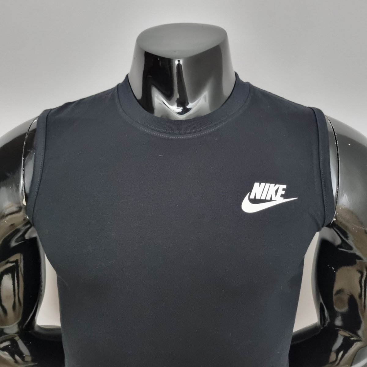 Chrome mannequin torso wearing a dark Nike sleeveless shirt with a white Nike swoosh logo on the chest.