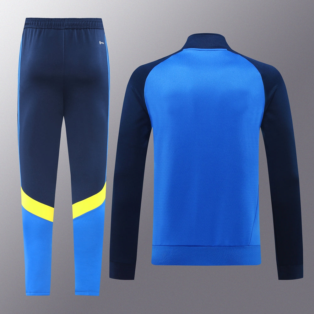 f93565bd | UAE SPORT STORE Blue athletic tracksuit: navy pants with a light blue lower section and a bright yellow knee band; matching blue jacket with dark sleeves.