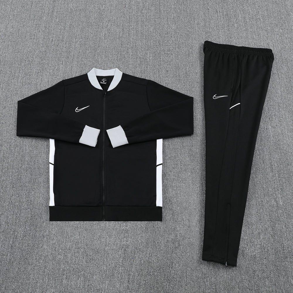 f9778eea | UAE SPORT STORE Black Nike track jacket with white cuffs and collar, paired with matching black pants, laid flat on a gray surface.