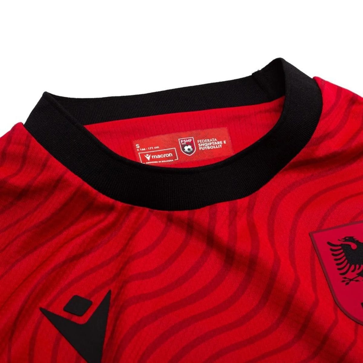 Close-up of a red striped shirt neckline with a black ribbed collar and a red care label visible inside the neck area.