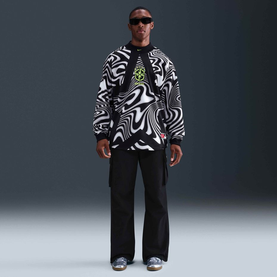 f9ede99d-f404-41e1-9ecf-c39a69218e49 | UAE SPORT STORE Male model in a black-and-white zebra-print sweatshirt with Brazil crest, black pants, and sunglasses.