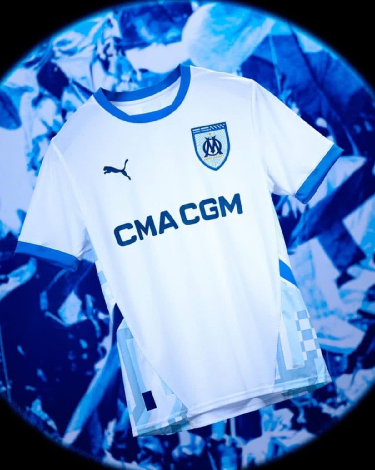 Marseille football jersey with club crest, Puma logo and CMA CGM sponsor, set against a blue abstract background.