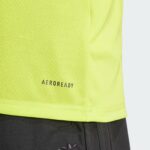 fFAWf6JusKmHbZW | UAE SPORT STORE Close-up of neon yellow athletic jersey fabric with the 'AEROREADY' logo near the hem and dark shorts below.