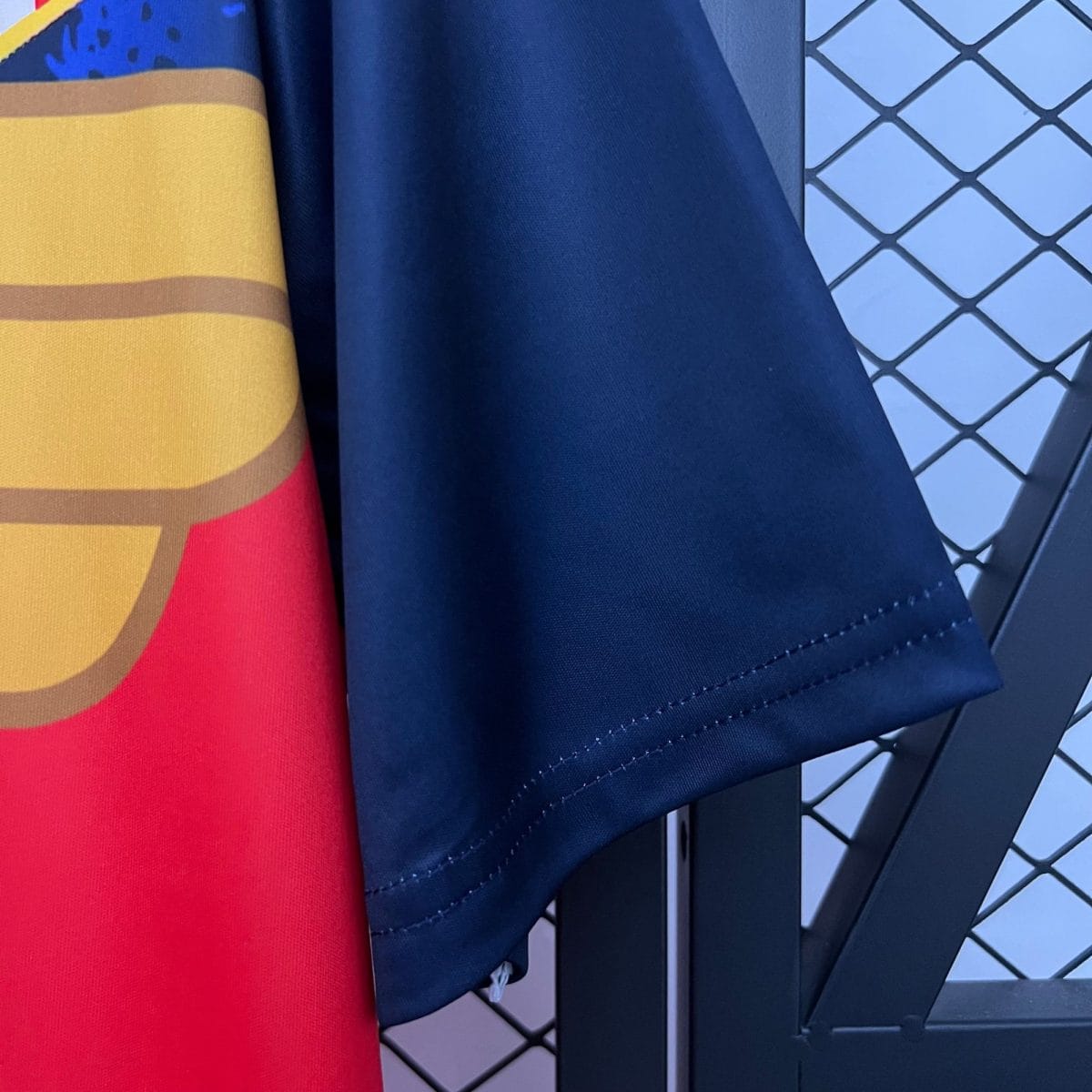 Close-up of overlapping fabrics: red/orange striped material on the left, dark blue fabric in the center, and a blue chain-link fence pattern on the right.