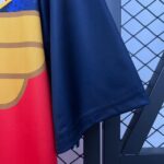 Close-up of overlapping fabrics: red/orange striped material on the left, dark blue fabric in the center, and a blue chain-link fence pattern on the right.
