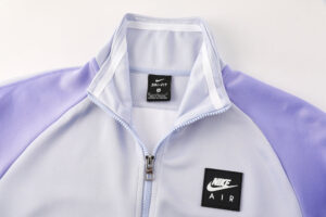 fab13d81 | UAE SPORT STORE Close-up of a lavender and light-gray Nike Air zip-up jacket, featuring a black Nike Air patch on the left chest and a front zipper.
