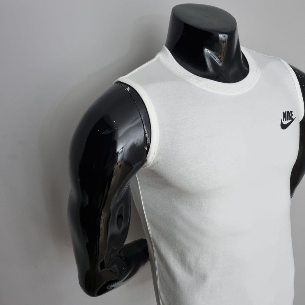White Nike sleeveless shirt worn on a black mannequin torso, Nike swoosh logo visible on the chest area.