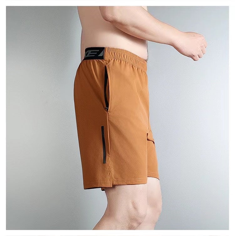 fb84e013 | UAE SPORT STORE Side view of a man wearing brown athletic shorts with zippered pockets and an elastic waistband.