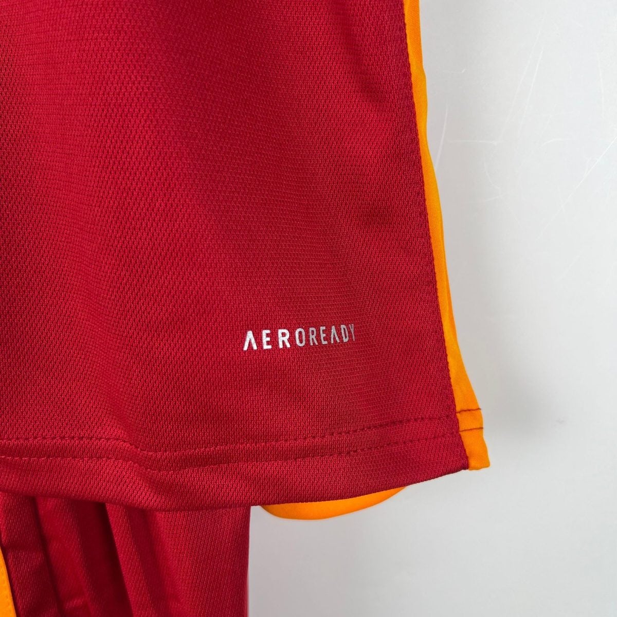 Close-up of a red fabric with orange trim along the edge, possibly part of a bag or athletic gear.