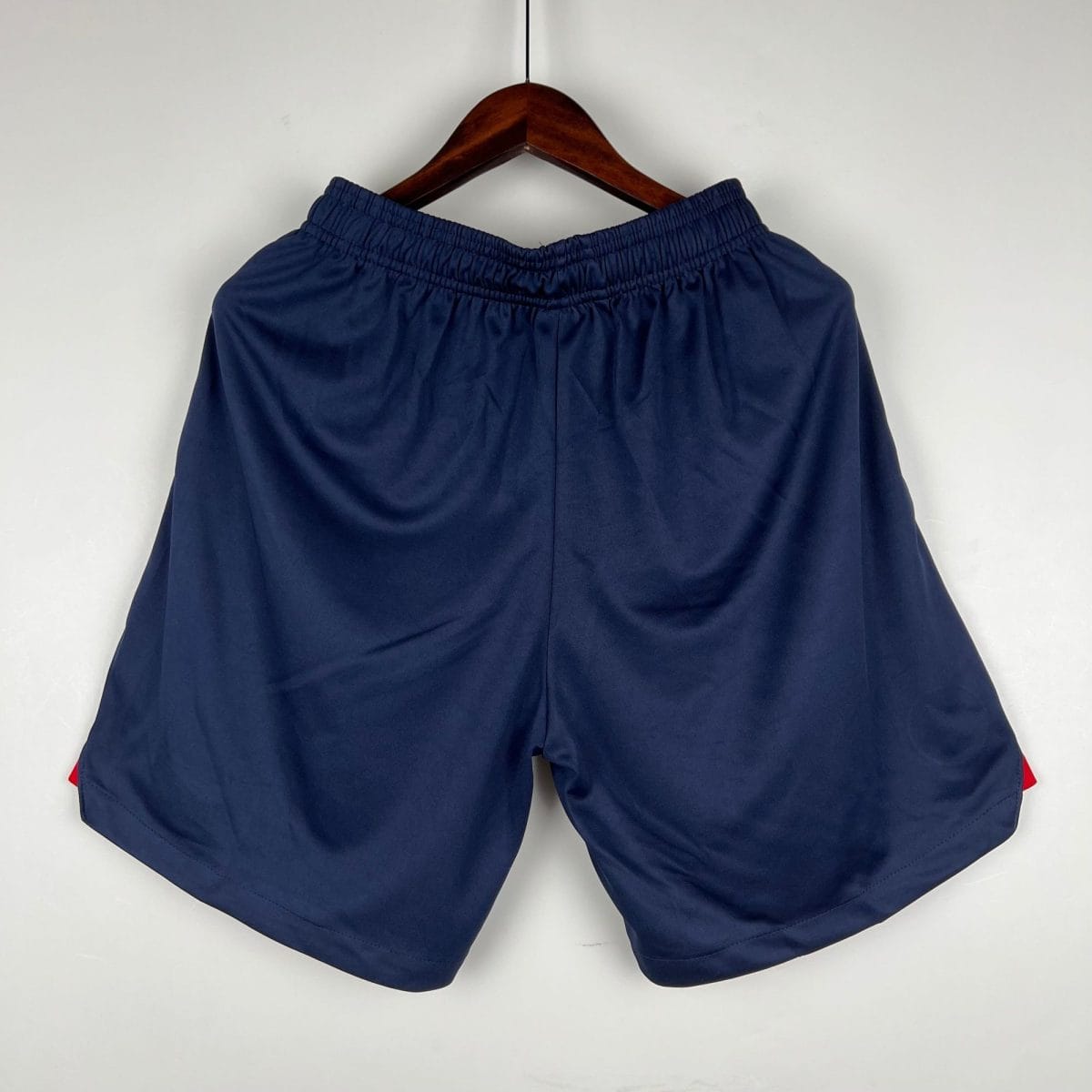 Navy blue elastic-waist shorts hanging on a wooden hanger against a light background.