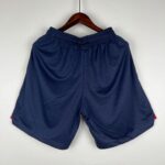 fbedad7e_7d20e6d2-922b-4d2e-a4fd-ad1c836c40cc | UAE SPORT STORE Navy blue elastic-waist shorts hanging on a wooden hanger against a light background.