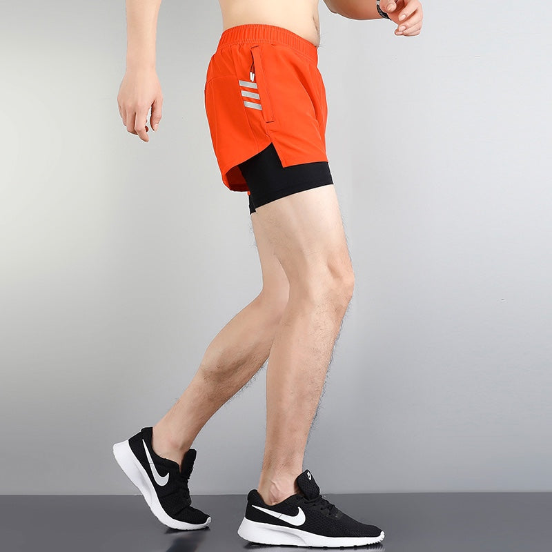 fbf8b508 | UAE SPORT STORE Person wearing bright orange athletic shorts over black compression shorts, paired with black Nike sneakers.