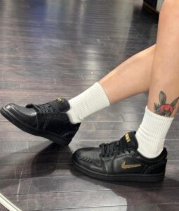Person wearing black Nike sneakers with white crew socks, showing a bunny tattoo on the ankle.