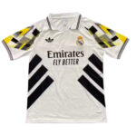 White Real Madrid Adidas football jersey with black geometric chevrons on the sleeves and sides, crest and 'Emirates Fly Better' sponsor text on front.